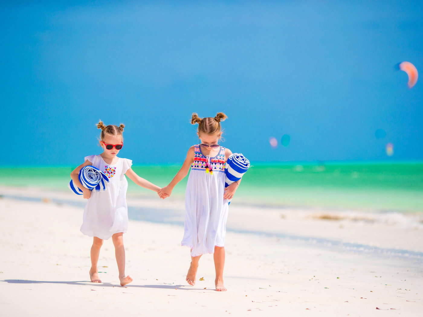 Две маленькие девочки идут по песку