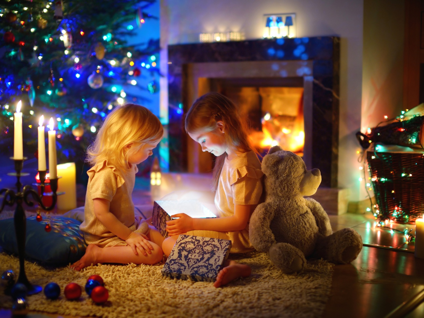 Две маленькие девочки с игрушками у камина