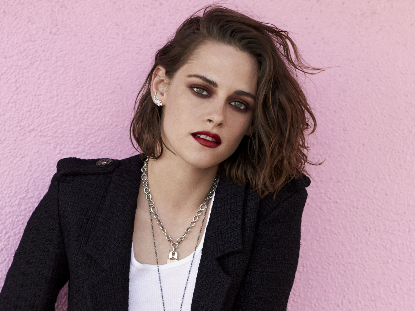 Актриса Кристен Стюарт в черном пиджаке на розовом фоне