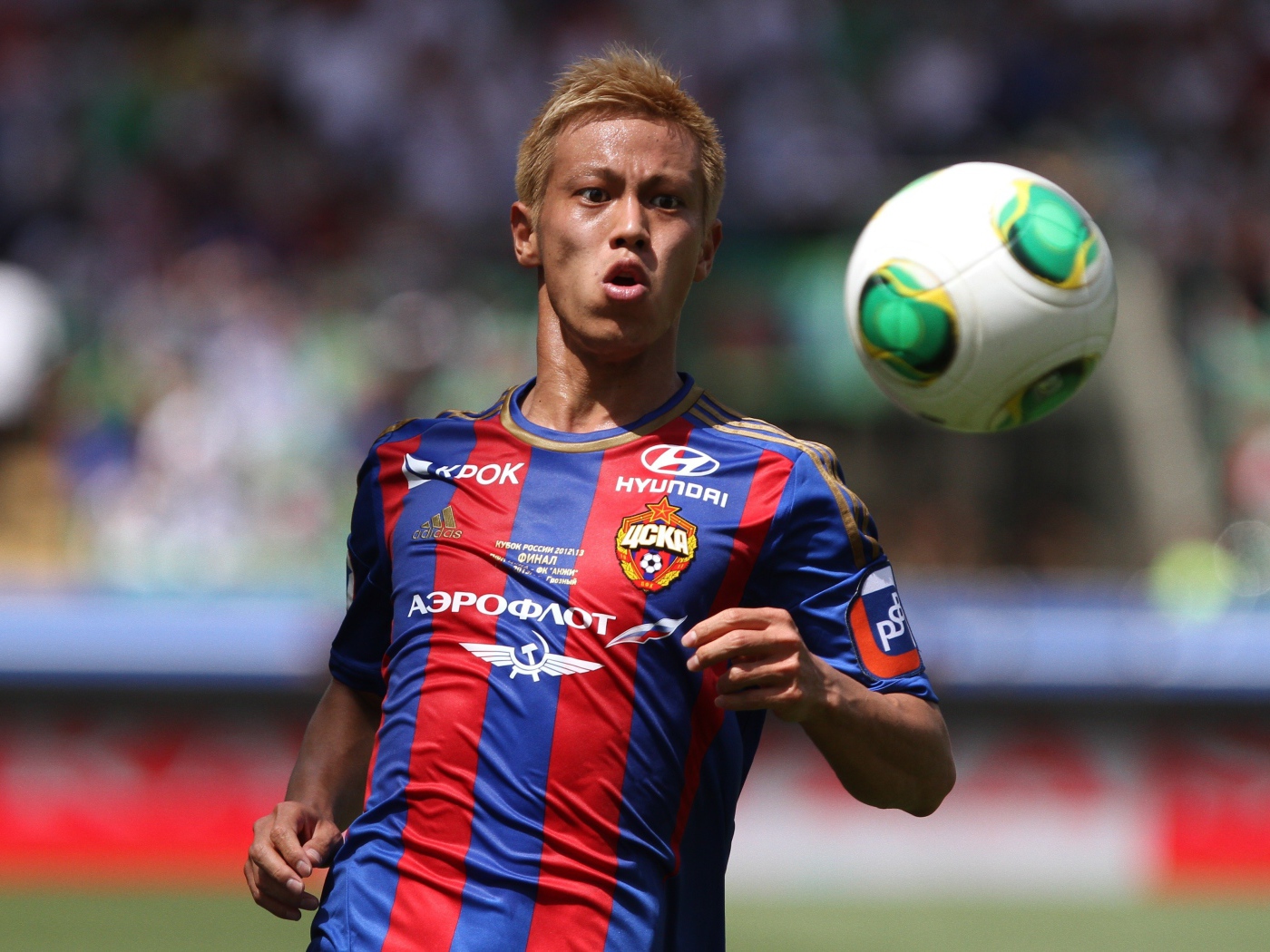 Японский футболист Кэйсукэ Хонда отбивает мяч на поле