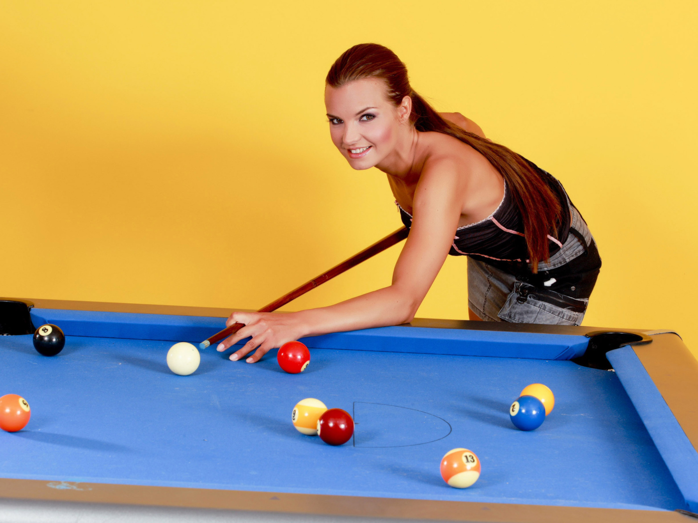 Молодая девушка играет в бильярд