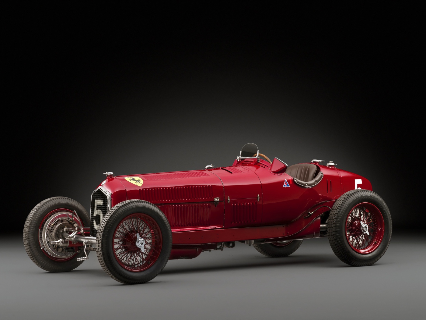 Красный ретро автомобиль Alfa Romeo на сером фоне