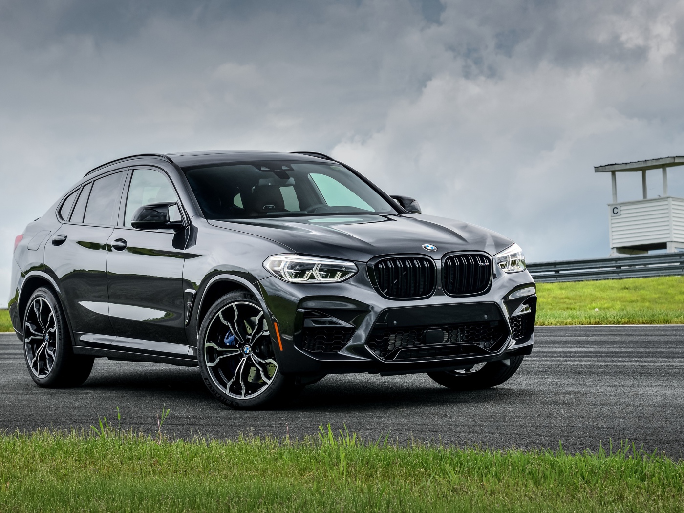 Черный автомобиль  BMW X4 M Competition, 2020 года на фоне грозового неба