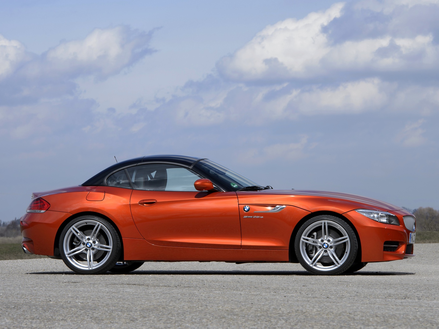 Оранжевый автомобиль BMW Z4 на фоне красивого неба