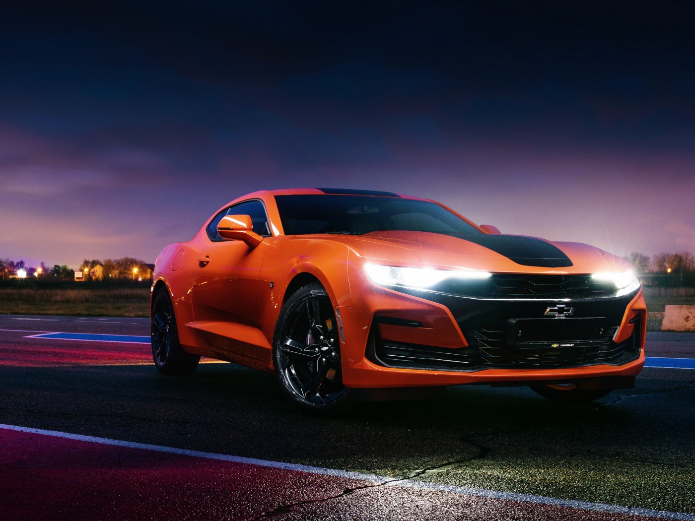 Оранжевый автомобиль Chevrolet Camaro, 2019 года с включенными фарами