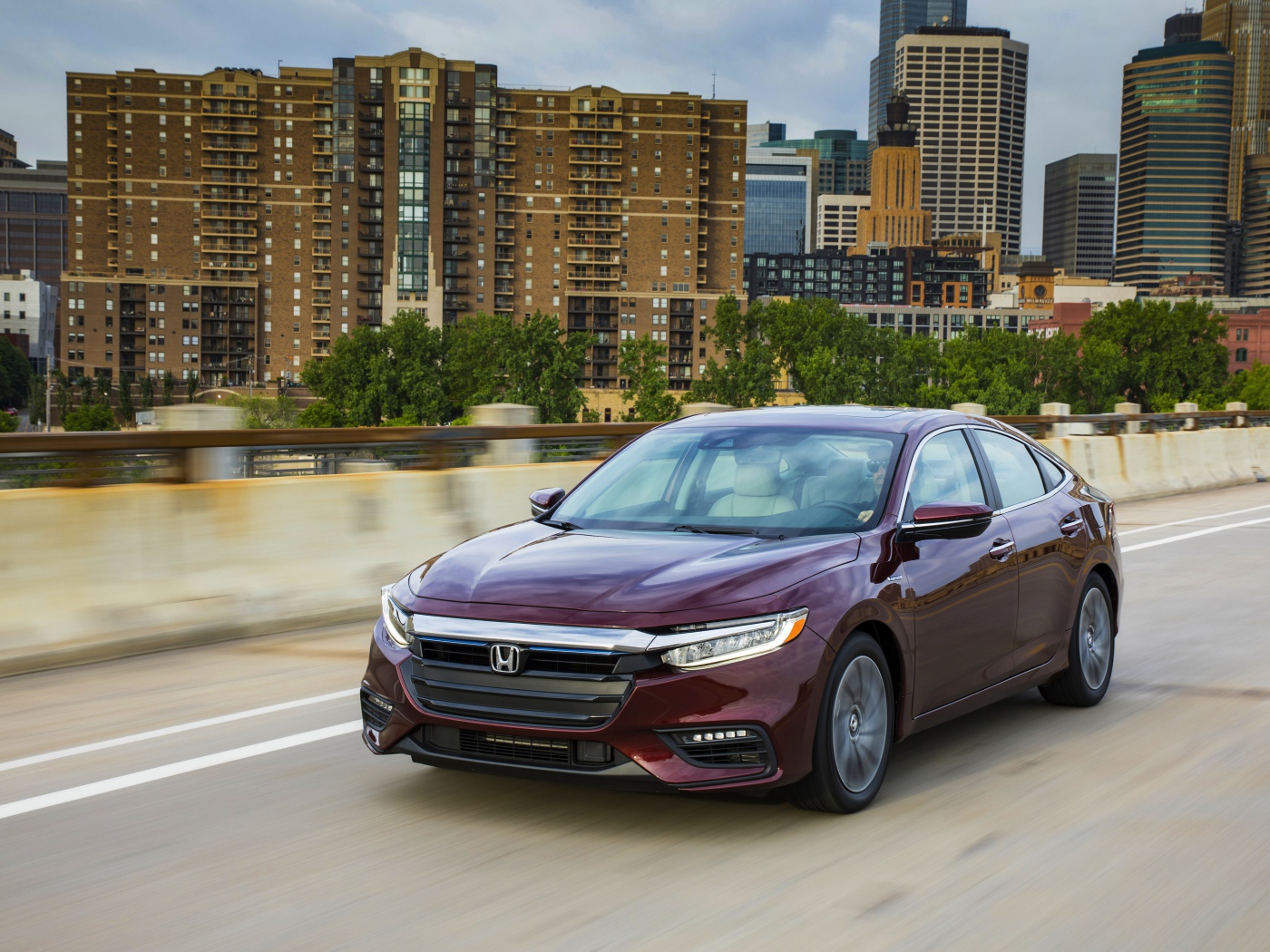 Бордовый автомобиль Honda Insight на фоне города