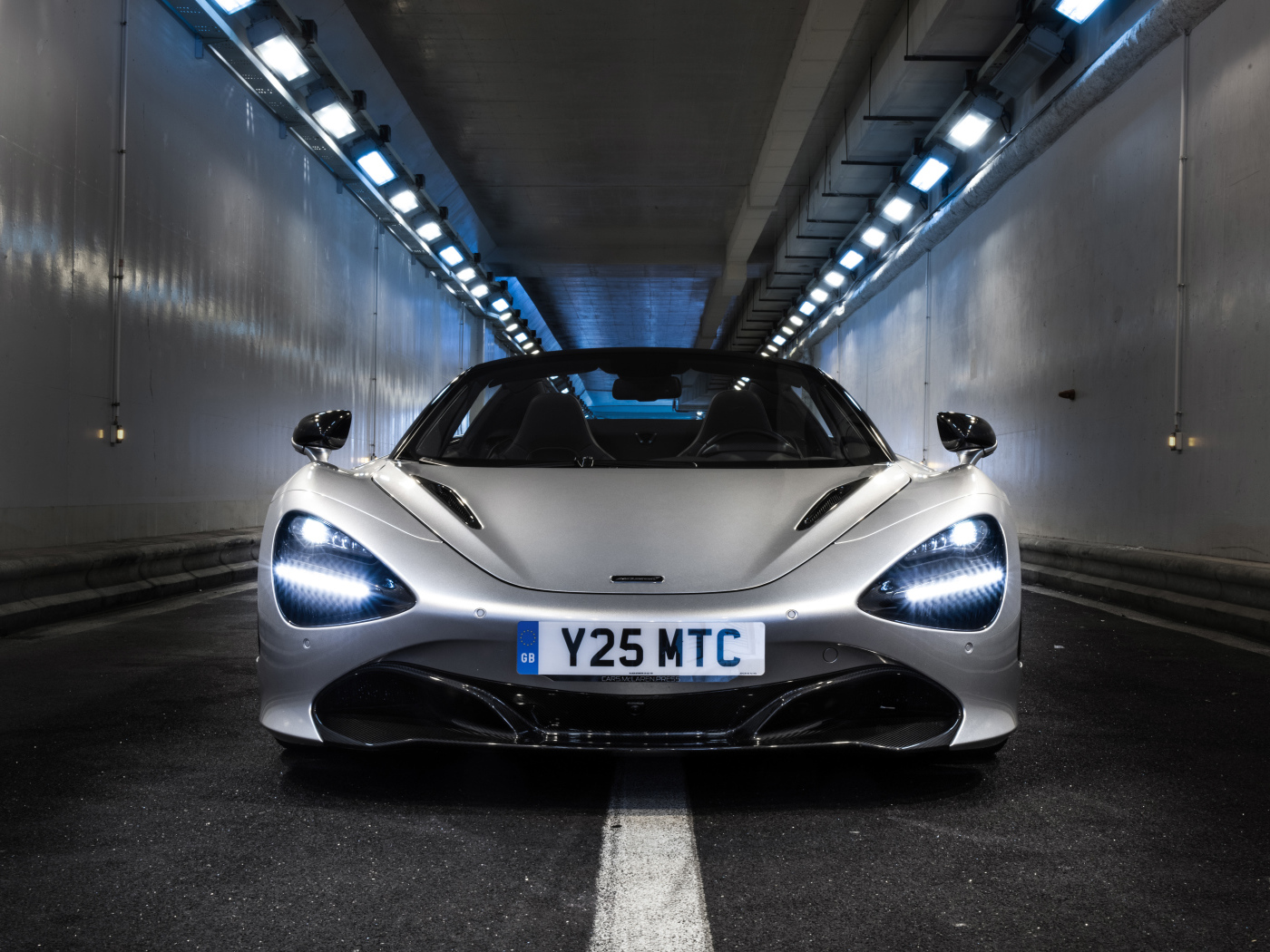 Серебристый спортивный автомобиль  McLaren 720S Spider, 2019 года в тоннеле