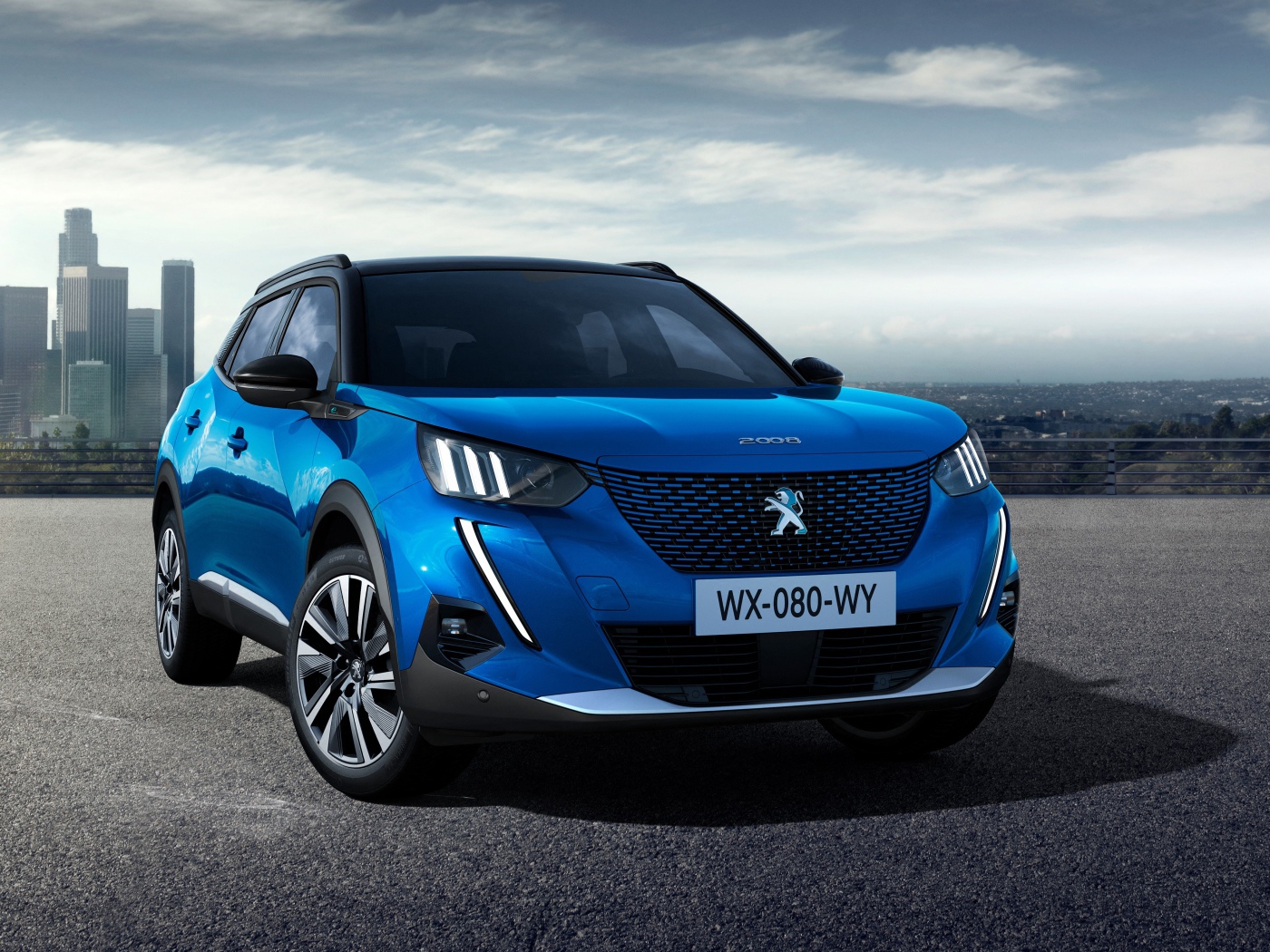 Синий внедорожник Peugeot E-2008 GT, 2019 года на фоне небоскребов