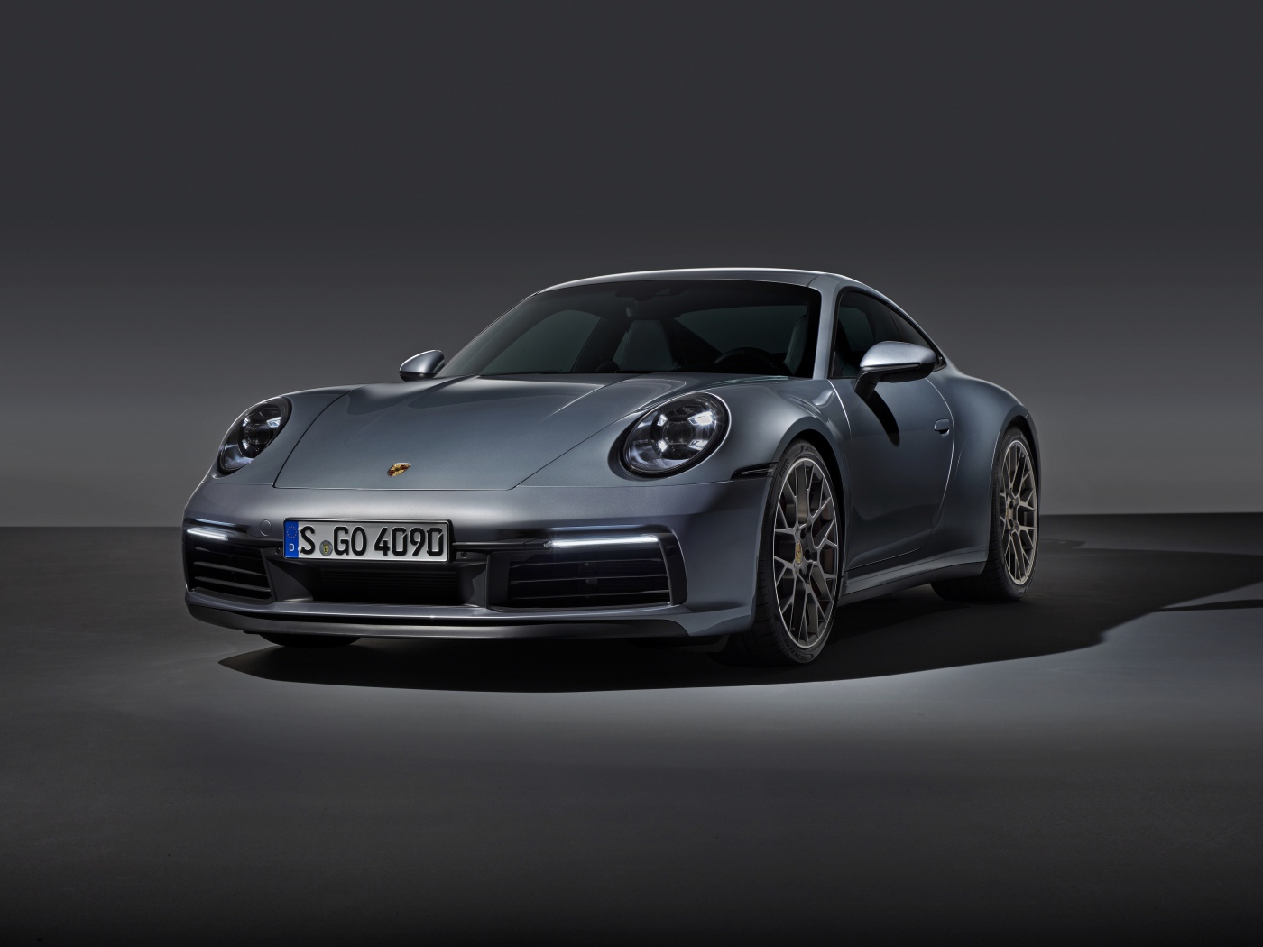 Серебристый автомобиль Porsche 911 Carrera 4S на сером фоне