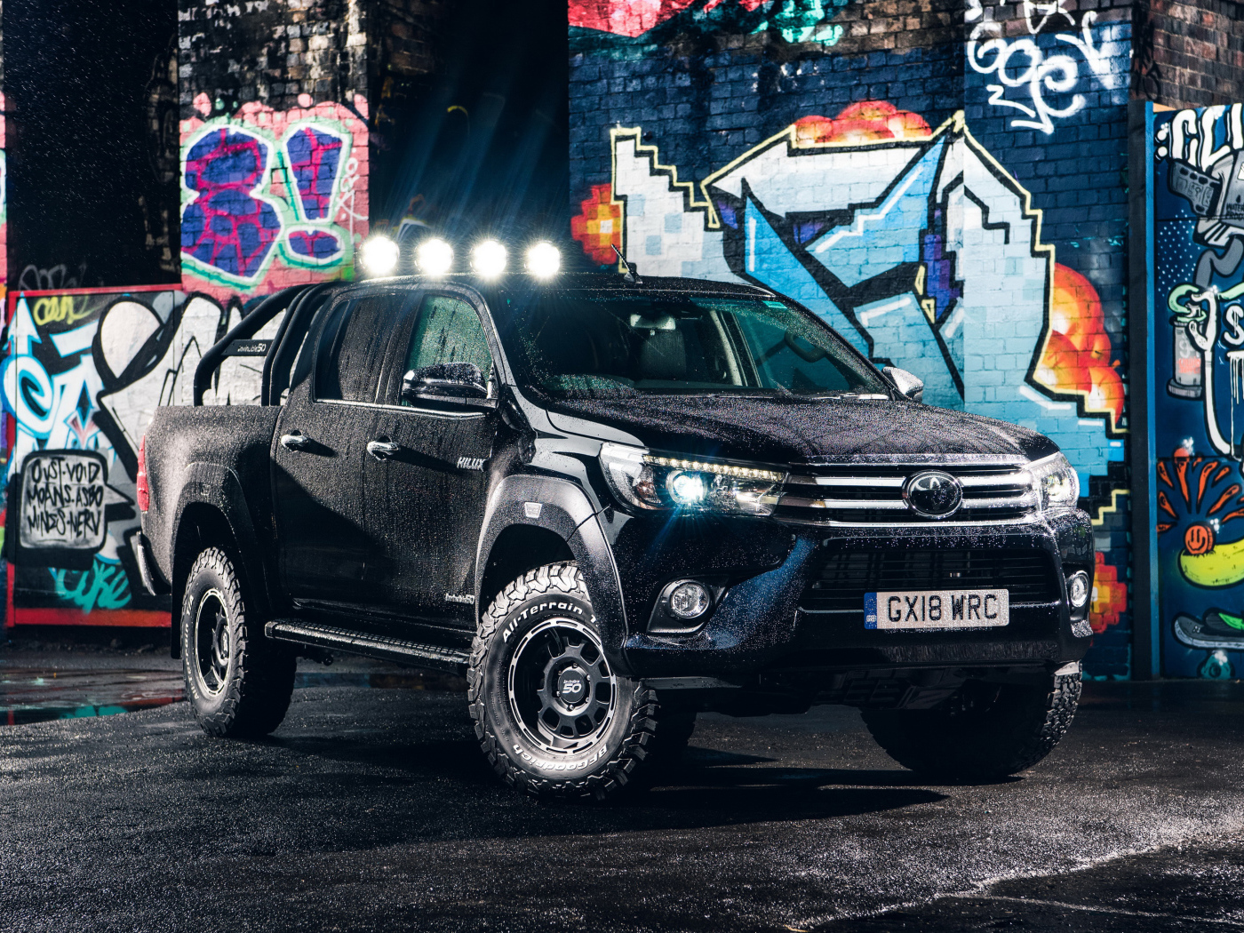 Black Toyota Hilux SUV in the rain against the backdrop of a painted wall