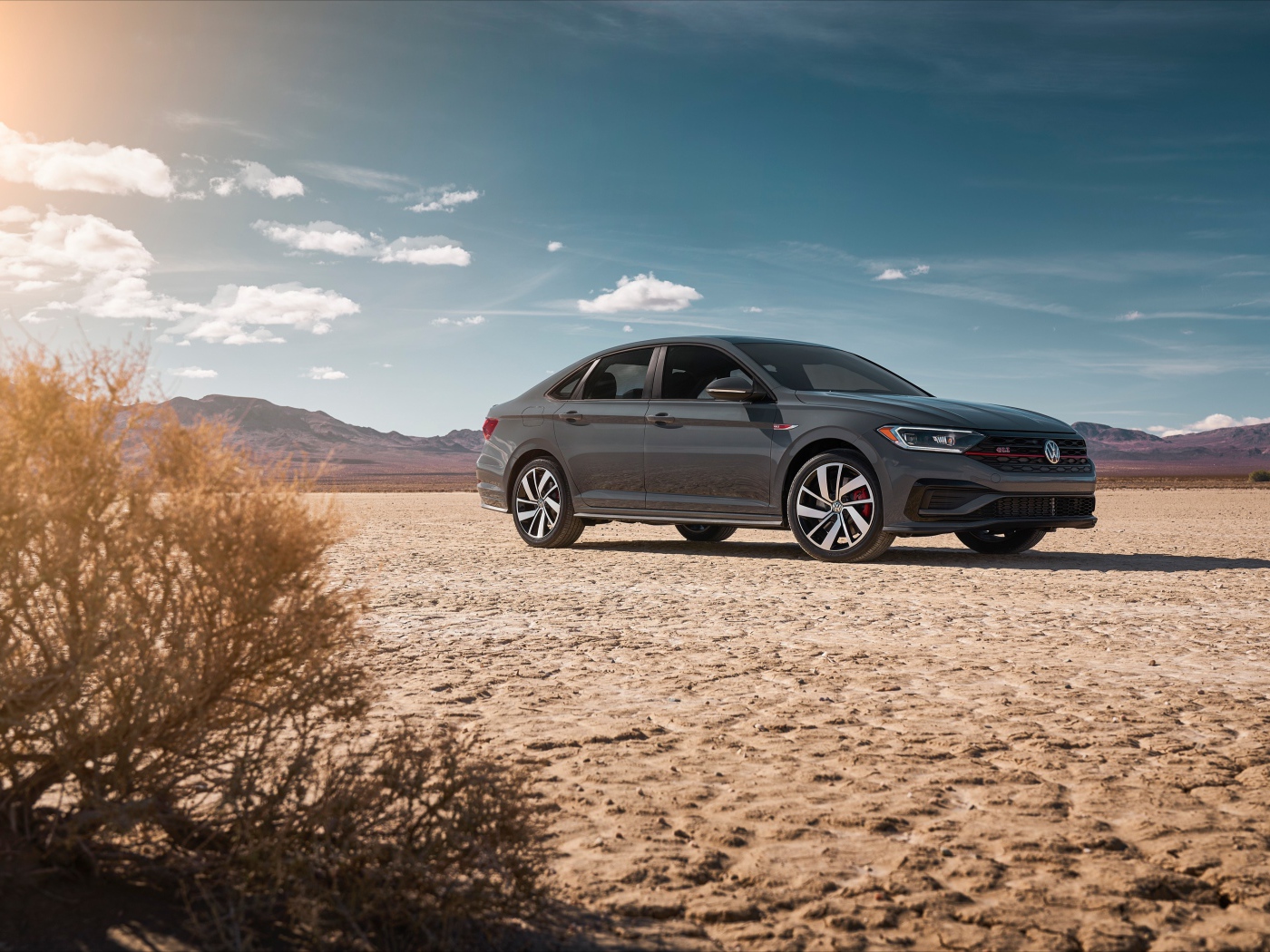 Стильный серебристый автомобиль Volkswagen Jetta на фоне неба 