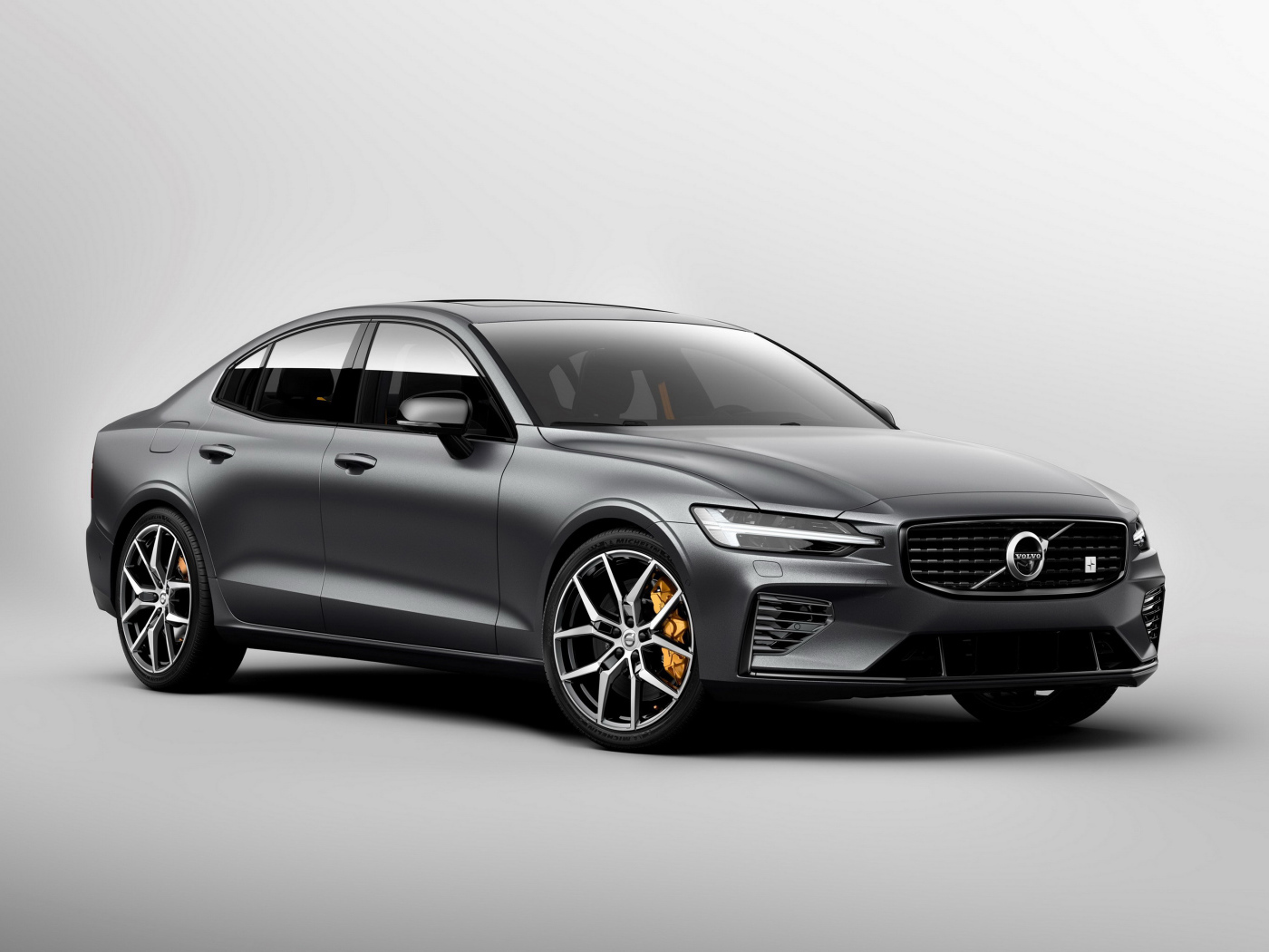 Серебристый автомобиль Volvo S60, 2018 года на сером фоне