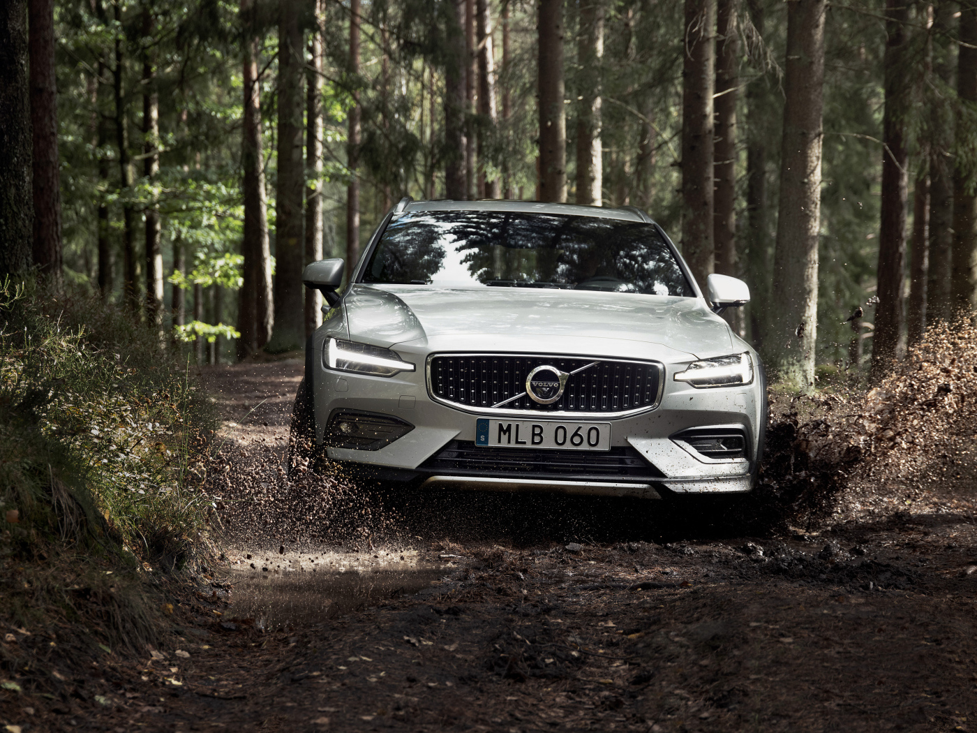 Silver car Volvo V60 T5 goes on a muddy forest road