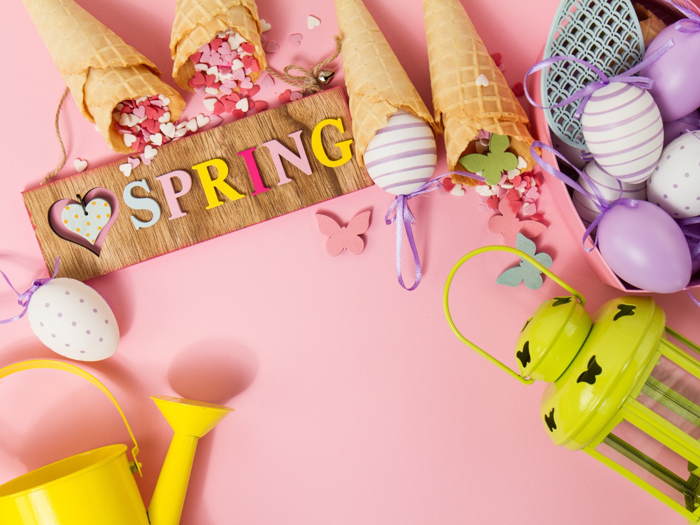 Надпись весна с вафельными рожками и яйцами на розовом фоне