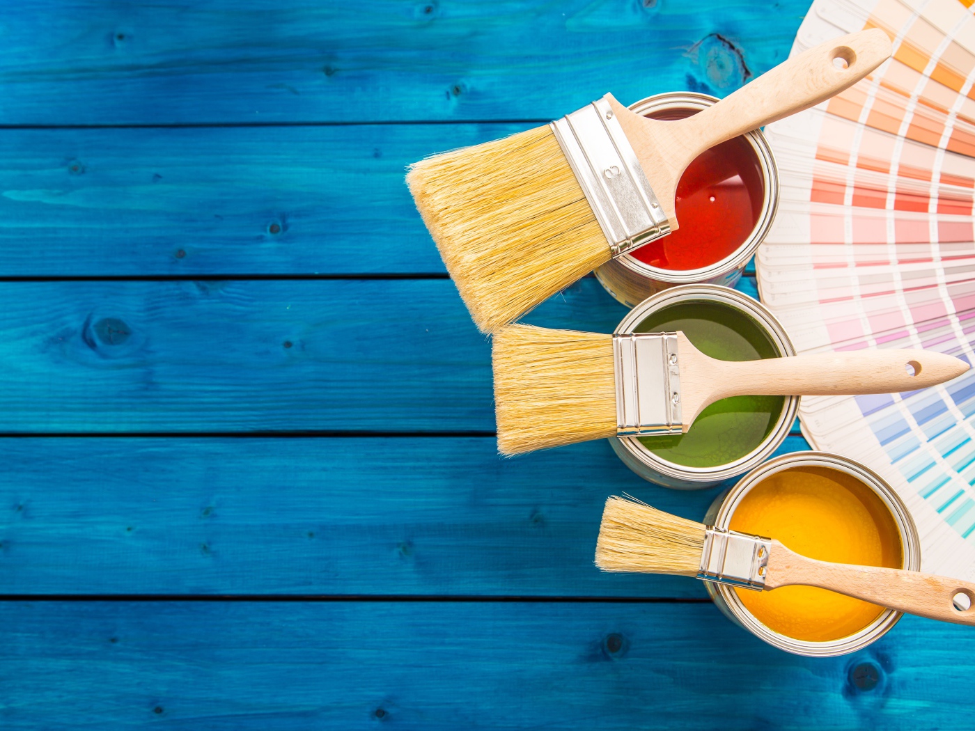 Три банки с краской и кистями на голубом фоне
