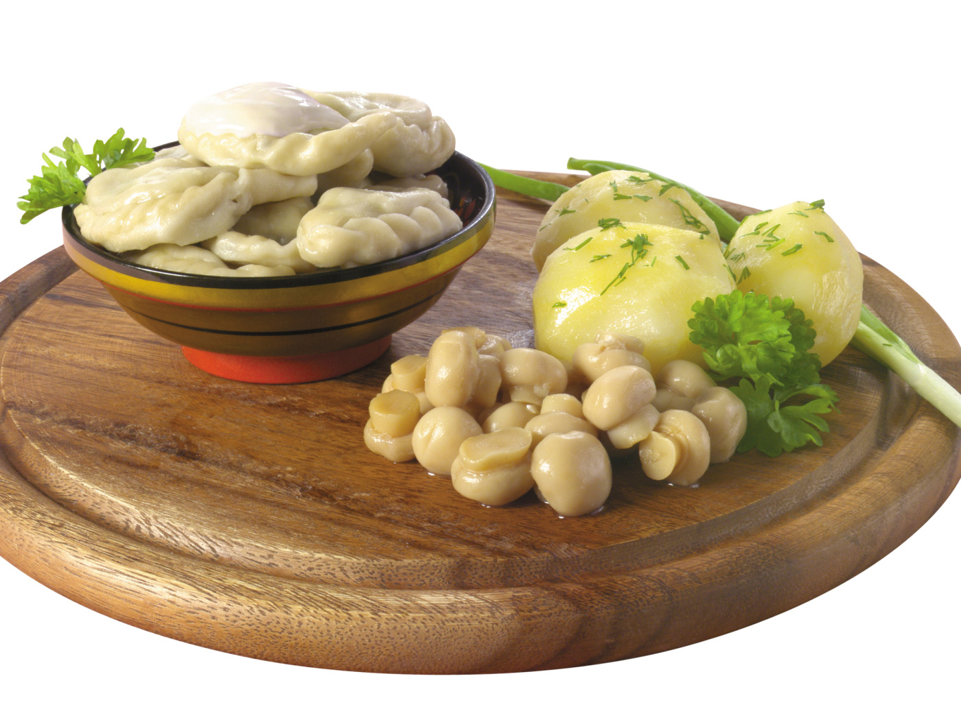 Вареники с грибами и вареной картошкой на деревянной доске на белом фоне