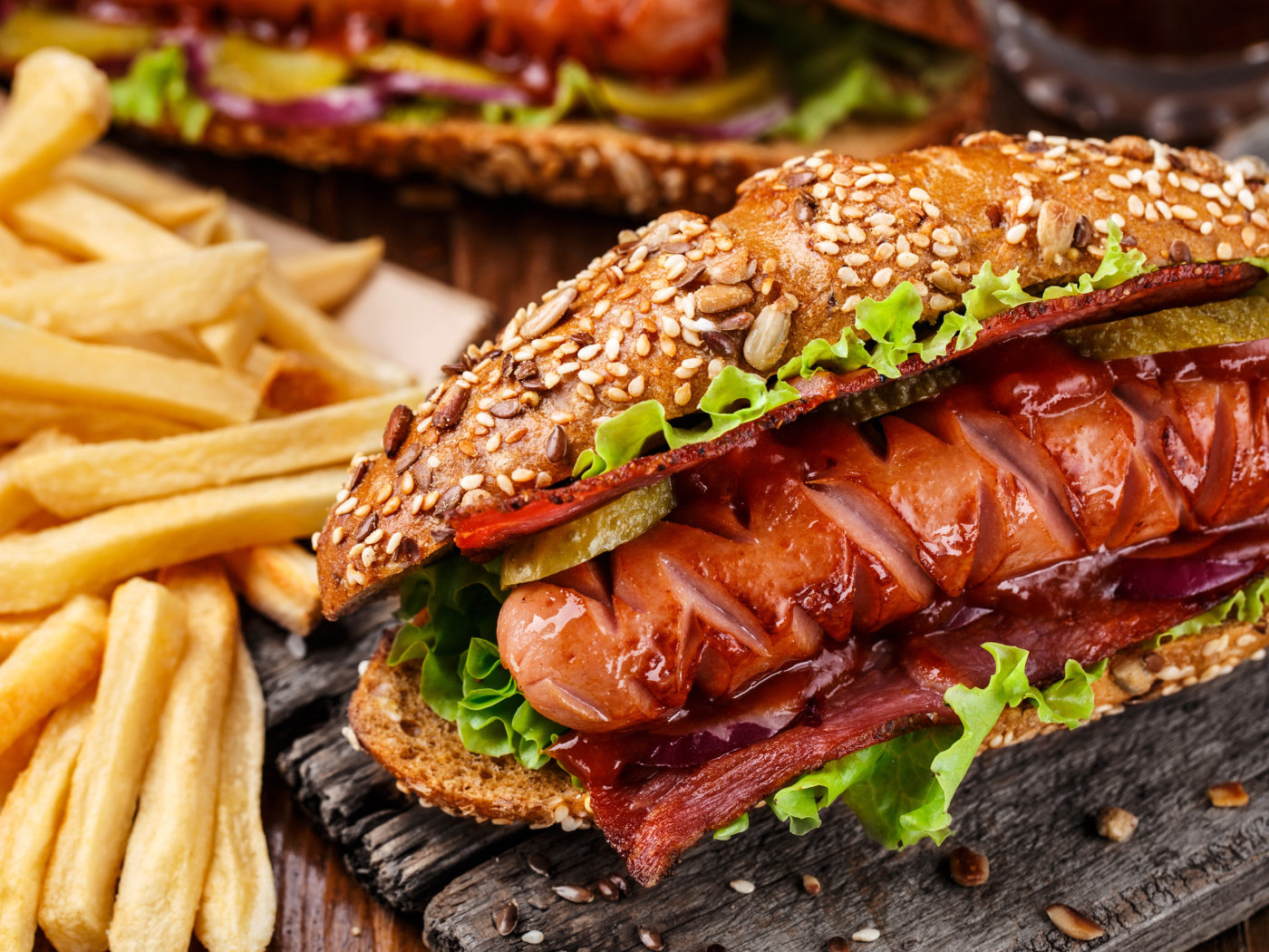 Хотдог с сосиской и беконом на столе с картофелем фри 