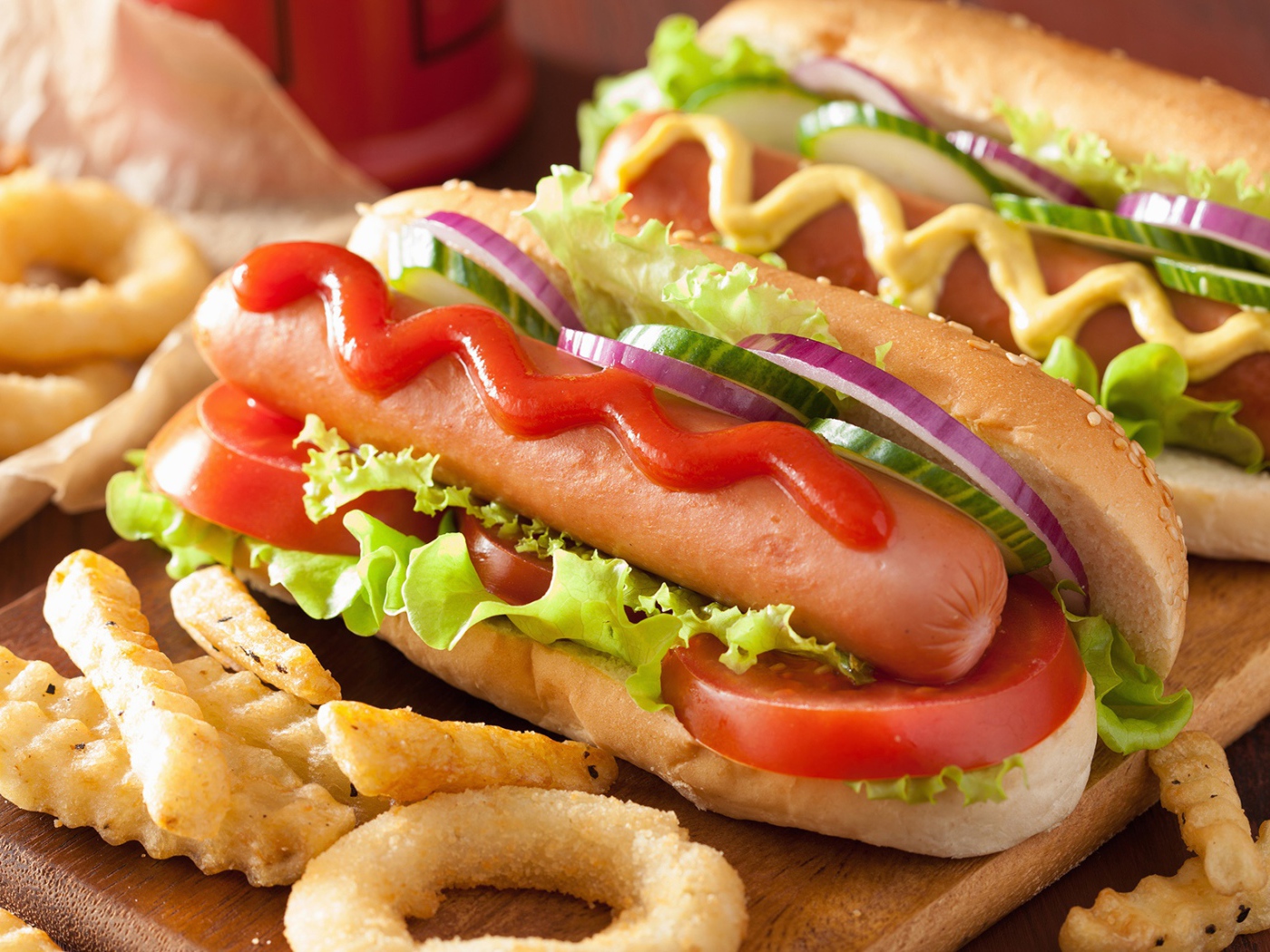 Хотдоги с овощами на разделочной доске с картофелем фри