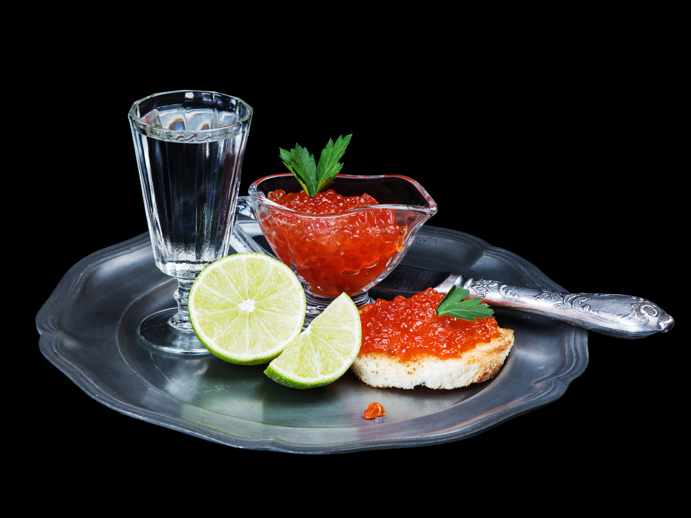 Бутерброды с красной икрой на подносе с рюмкой водки и лаймом