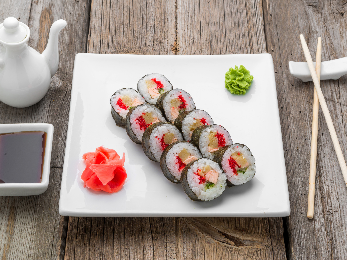 Суши на большой белой тарелке с соусом васаби и имбирем на столе соевым соусом