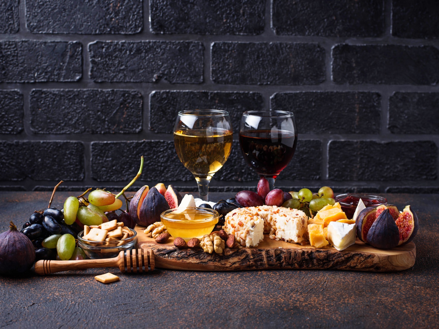 Два бокала вина на столе с сыром, инжиром и виноградом