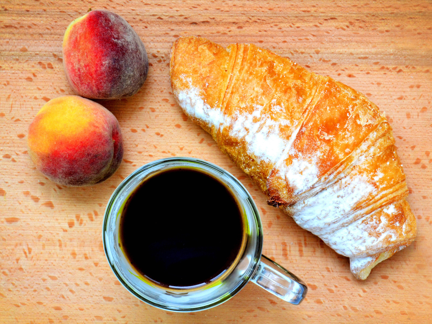 Два персика на столе с кофе и круассаном