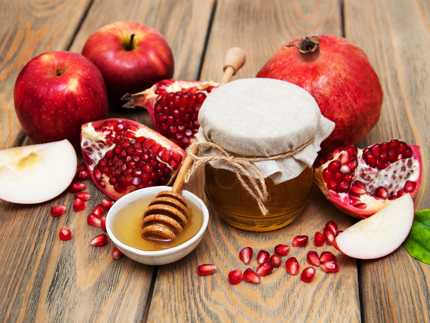 Банка меда на столе с гранатами и яблоками