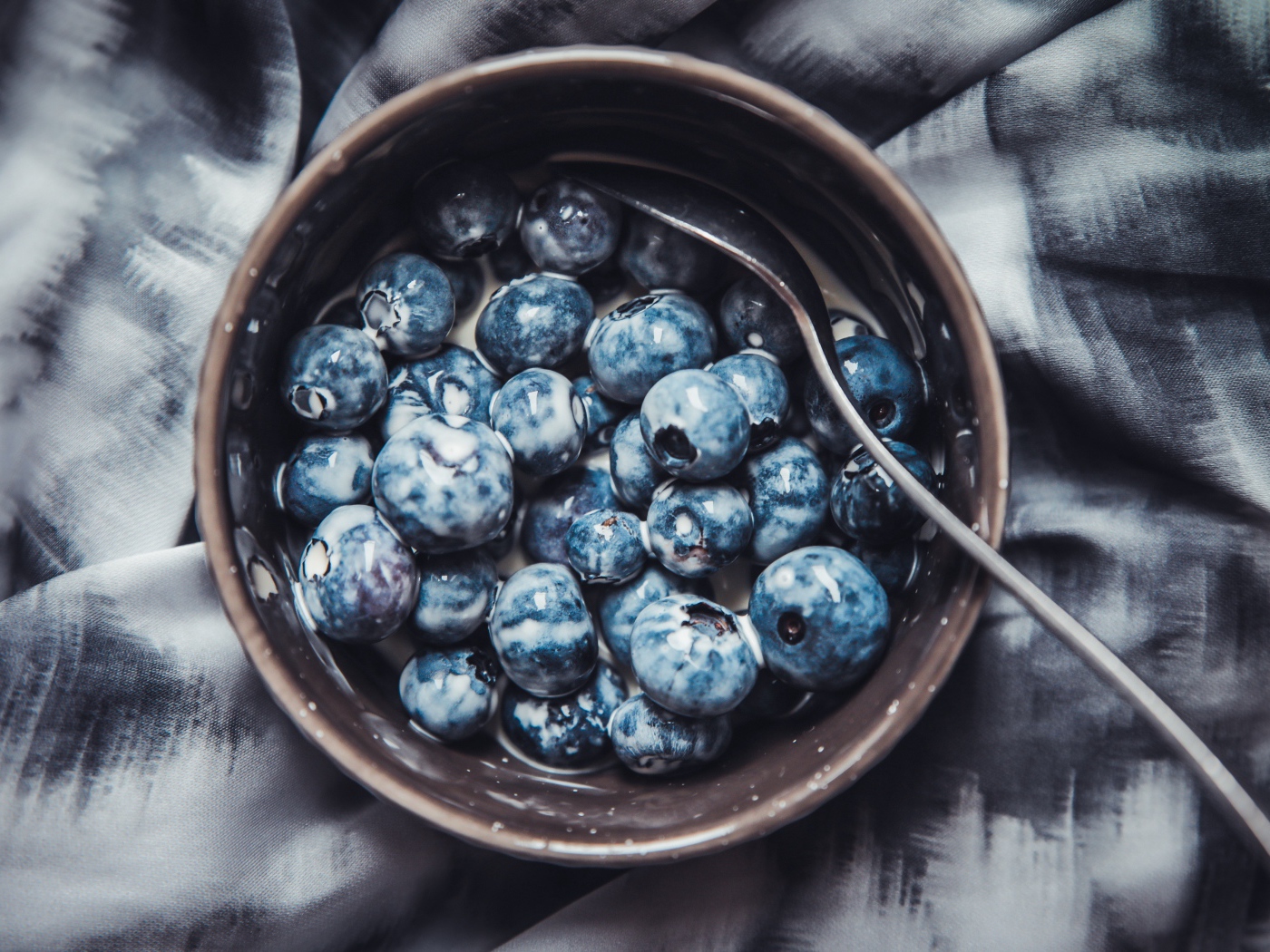 Черника в миске с йогуртом и ложкой