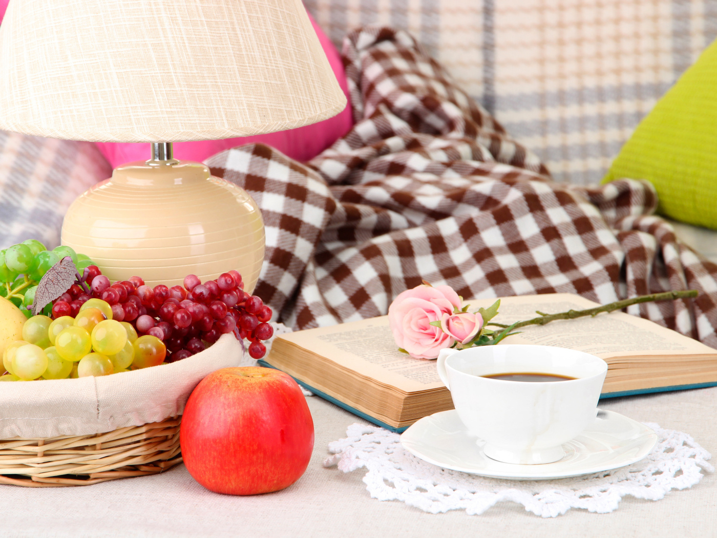 Фрукты в корзине на столе с книгой, чашкой кофе и розой
