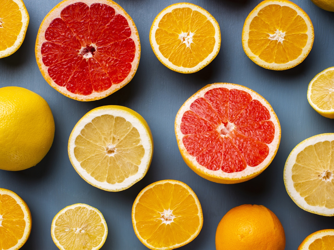 Лимоны, грепфрукты и апельсины на сером фоне