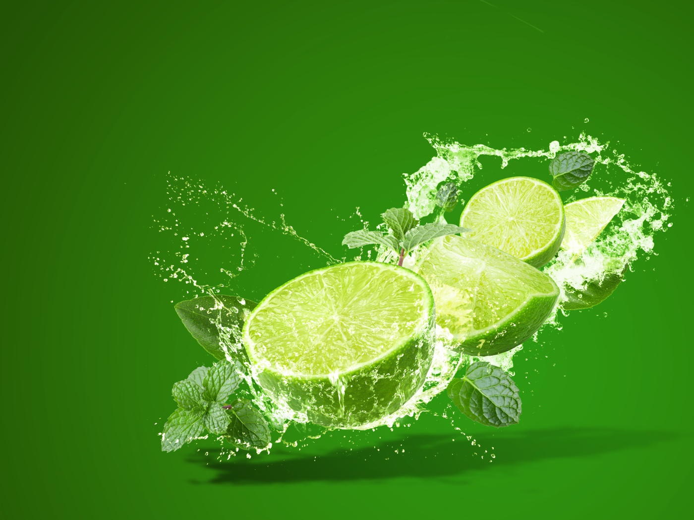 Лайм с мятой в брызгах воды на зеленом фоне
