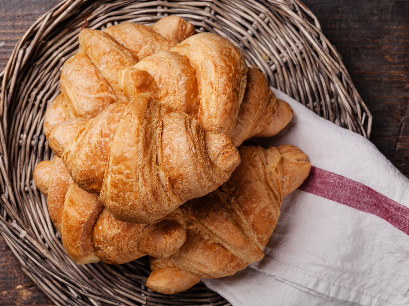 Fresh croissants in a wicker basket with a towel