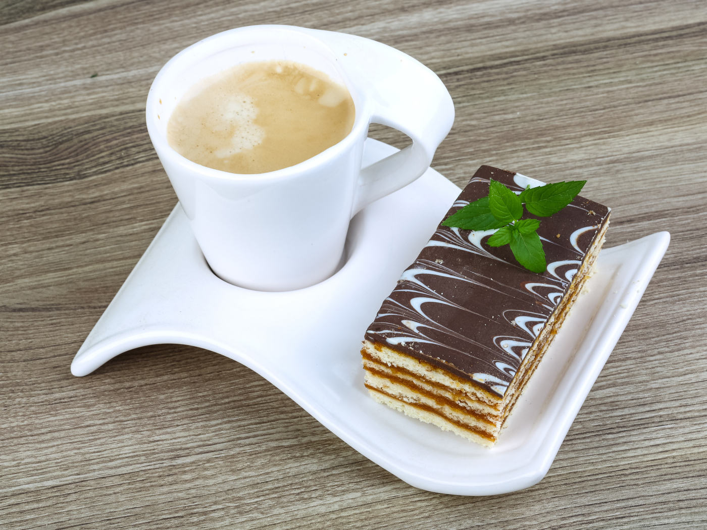 Чашка капучино на тарелке с пирожным 