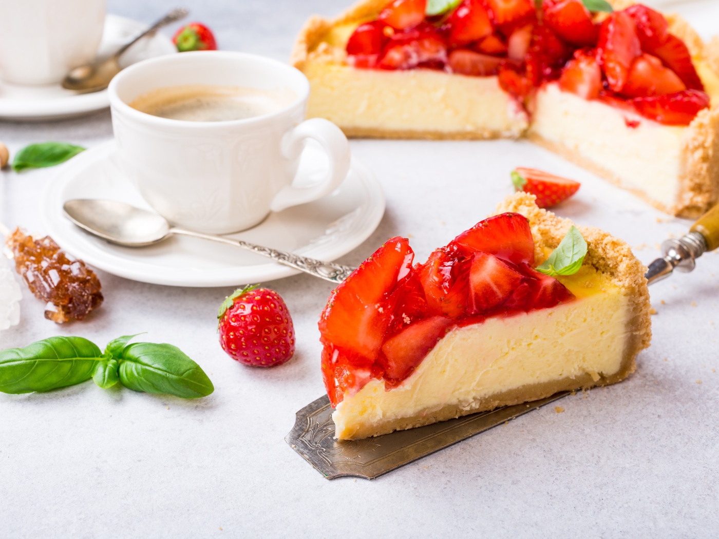 Кусок чизкейка с клубникой на столе с кофе
