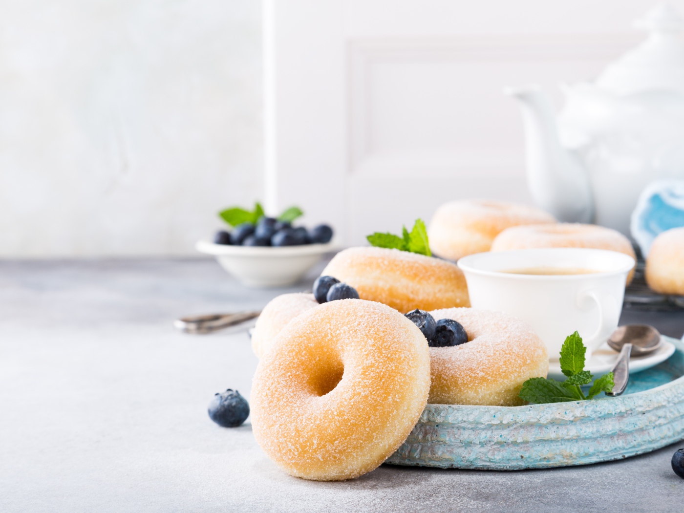 Аппетитные пончики с сахарной пудрой на столе с черникой