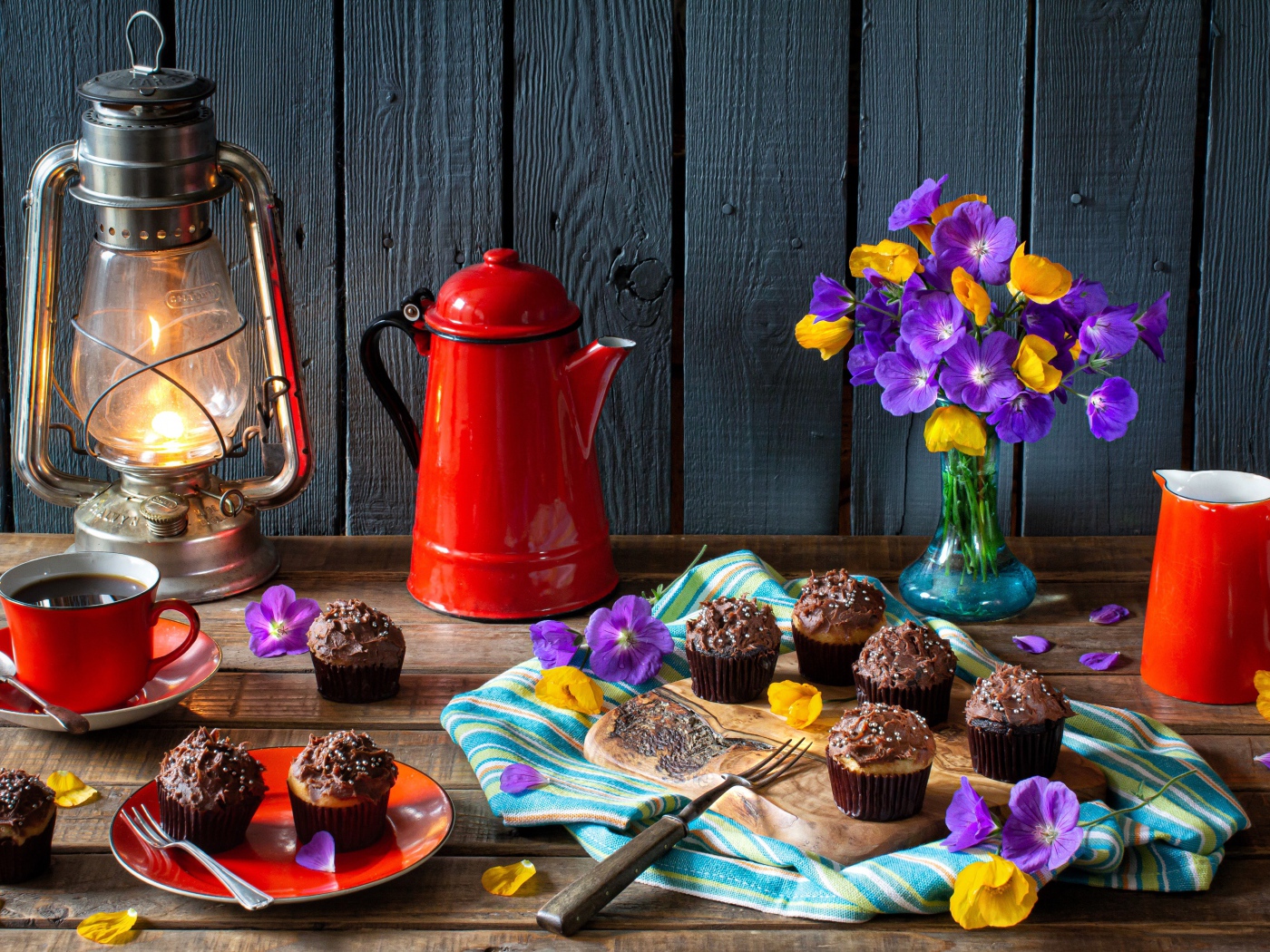 Аппетитные свежие кексы с кремом на столе с кофе, лампой и букетом цветов