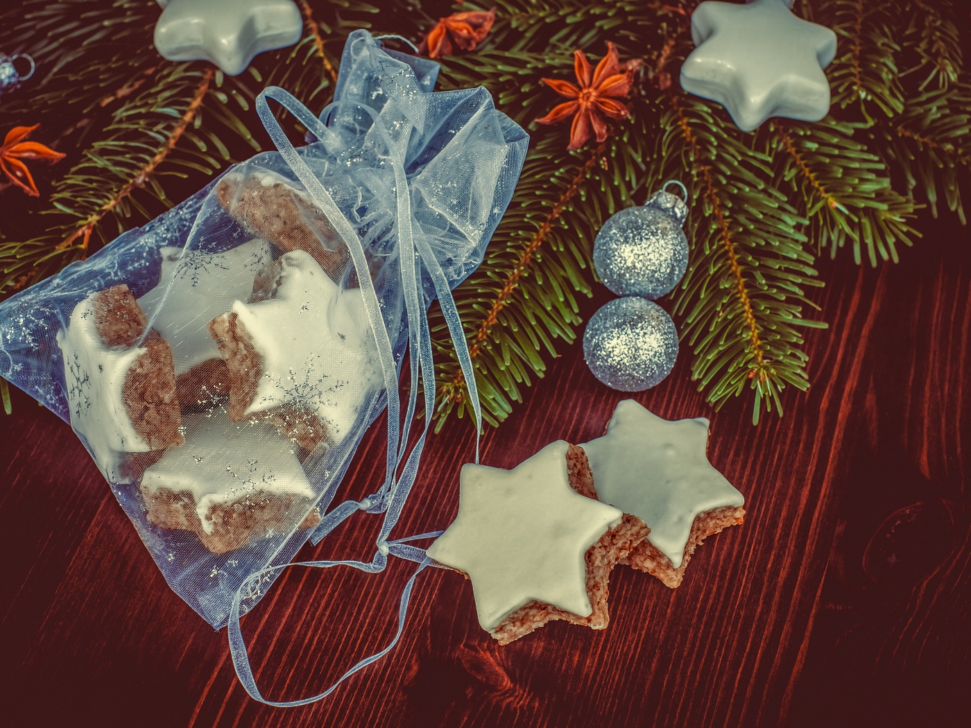 Аппетитное печенье звездочки в мешочке на столе с еловой веткой