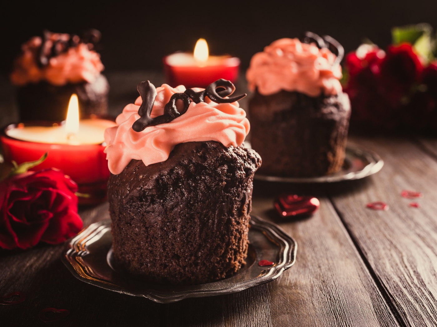 Шоколадные кексы с кремом на столе со свечами и розами