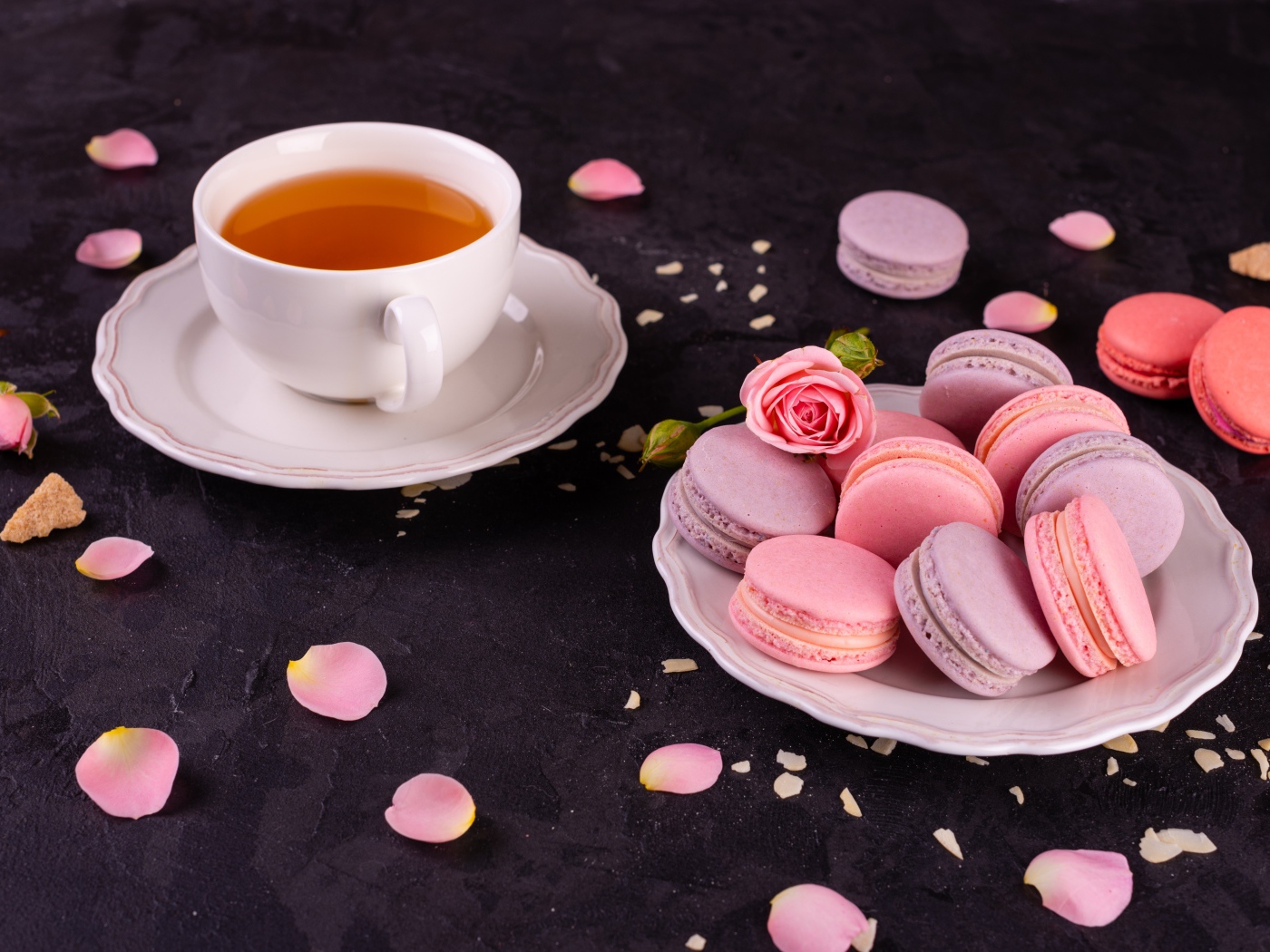 Нежный десерт макарон на столе с чашкой чая и розой