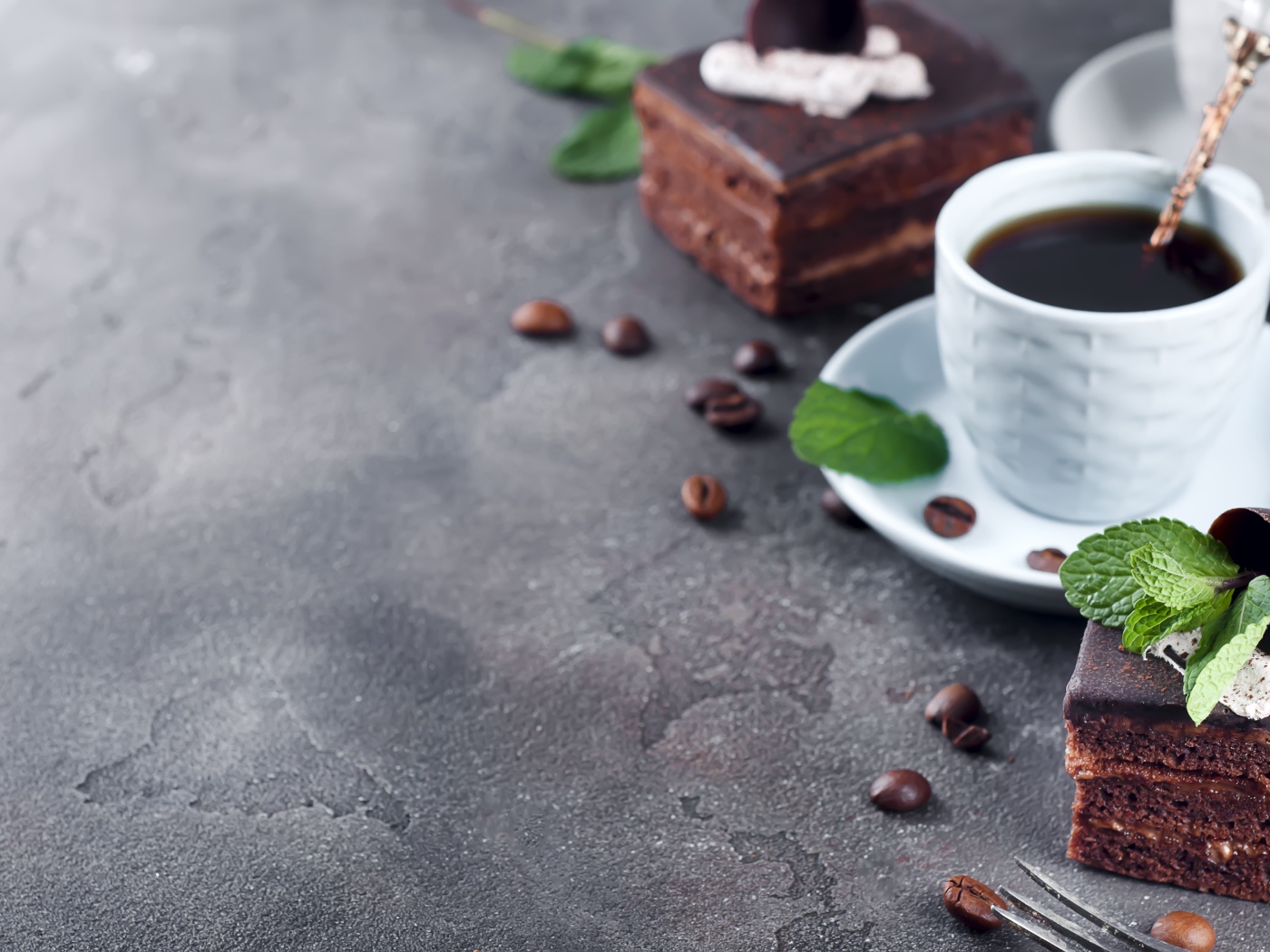 Аппетитное шоколадное пирожное на сером столе с чашкой кофе