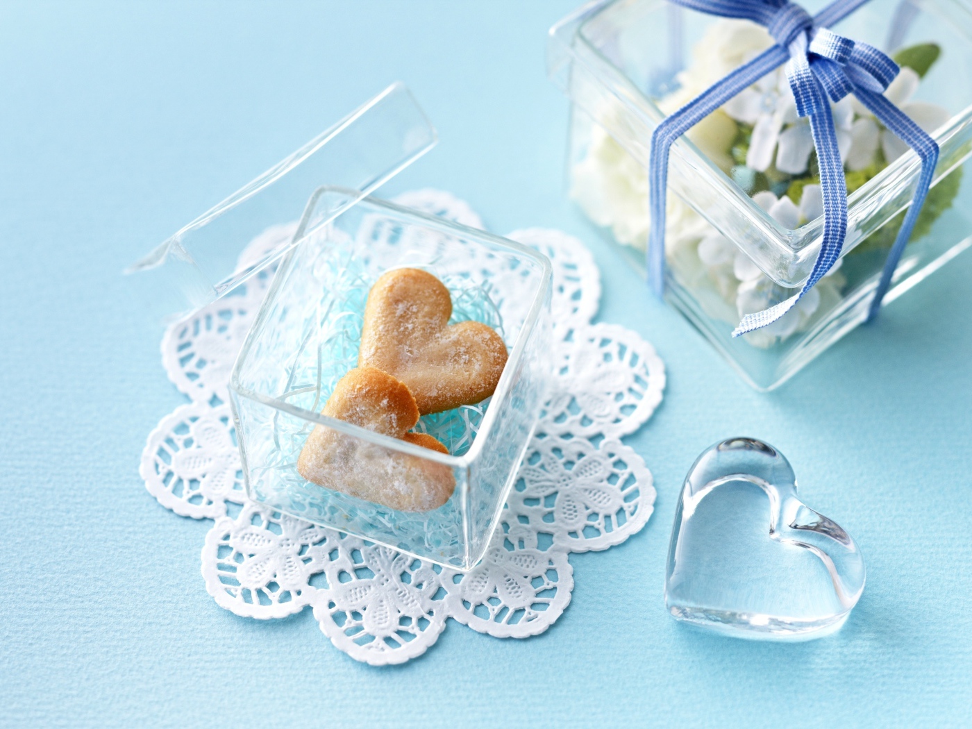 Песочное печенье в форме сердца в стеклянной шкатулке на голубом столе 