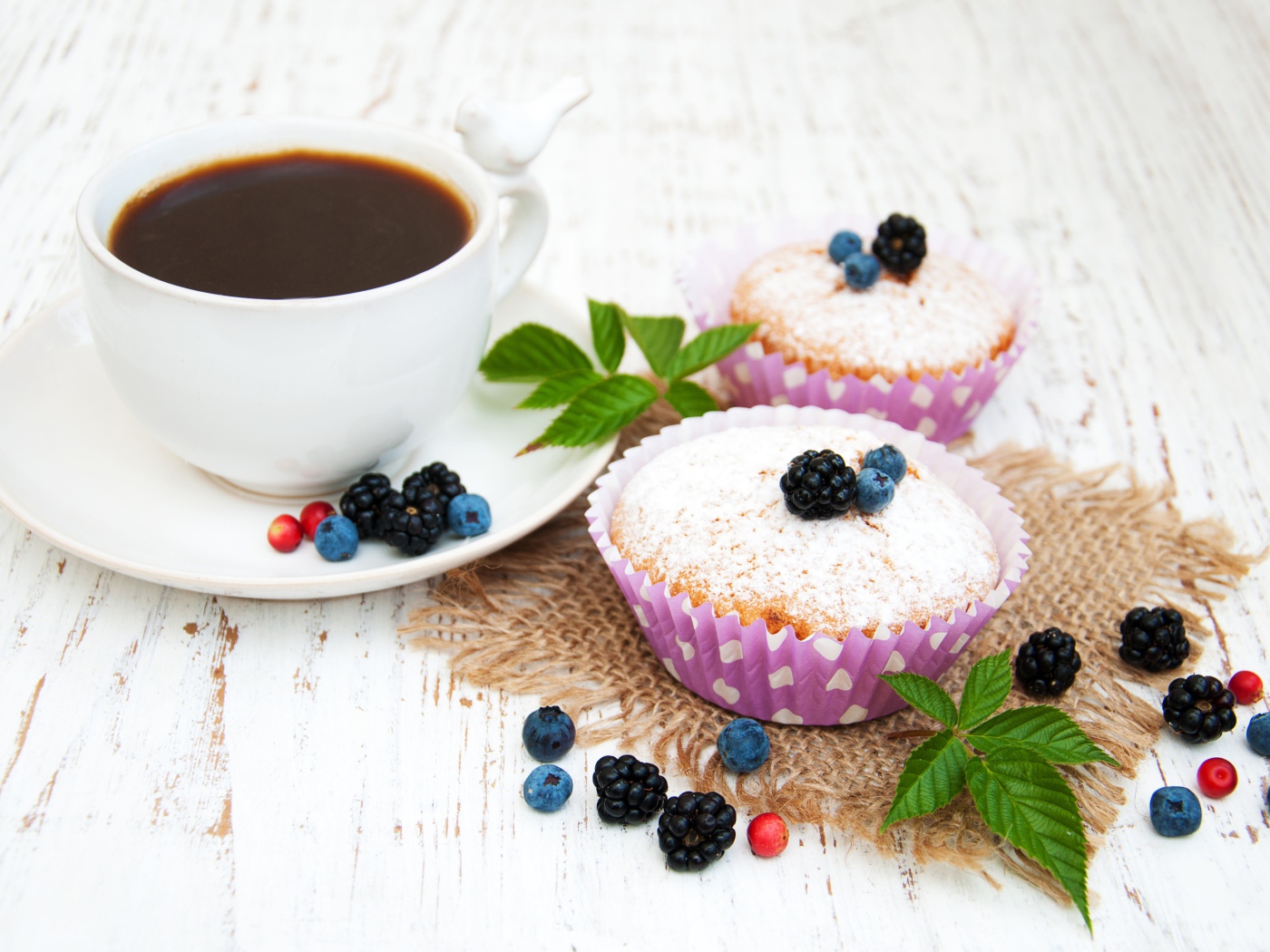 Кексы с сахарной пудрой и ягодами на столе с какао