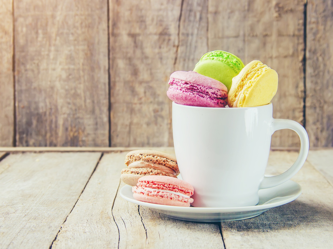 Разноцветный десерт макарон в белой чашке на столе