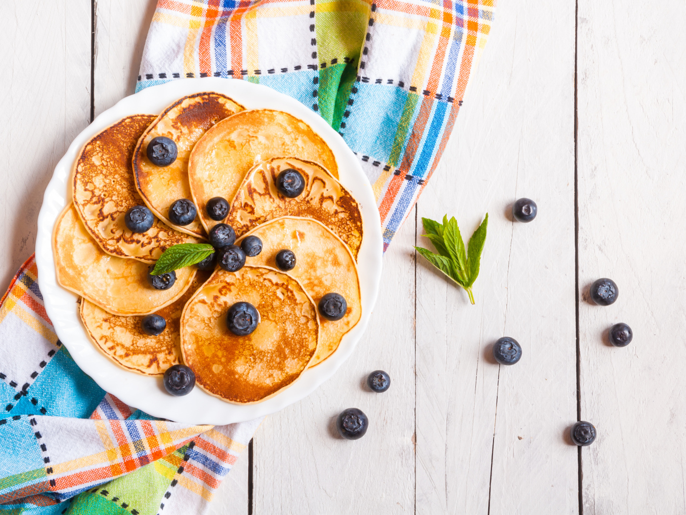 Румяные оладьи на тарелке с ягодами черники