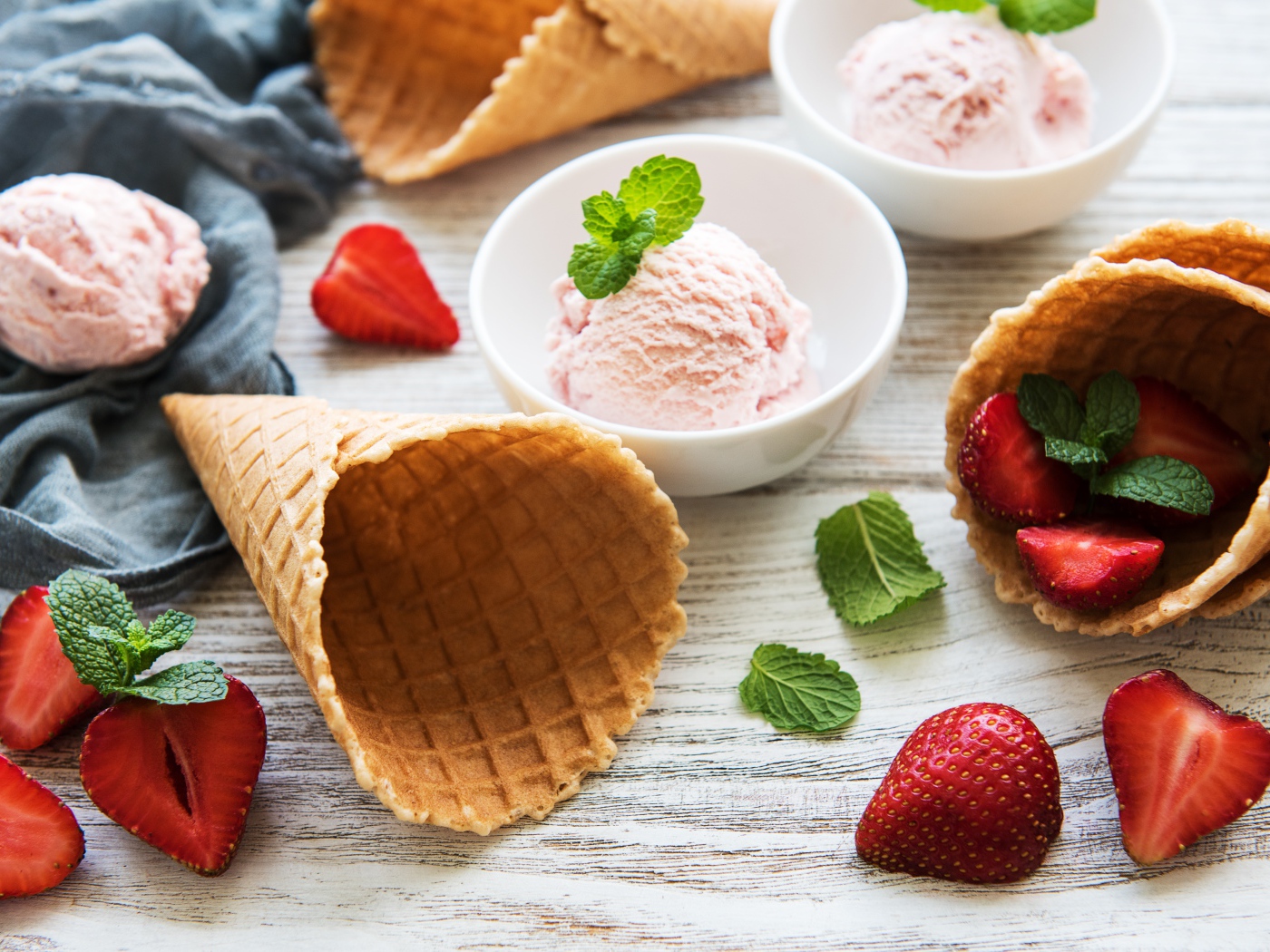 Клубничное мороженое на столе с рожками и клубникой