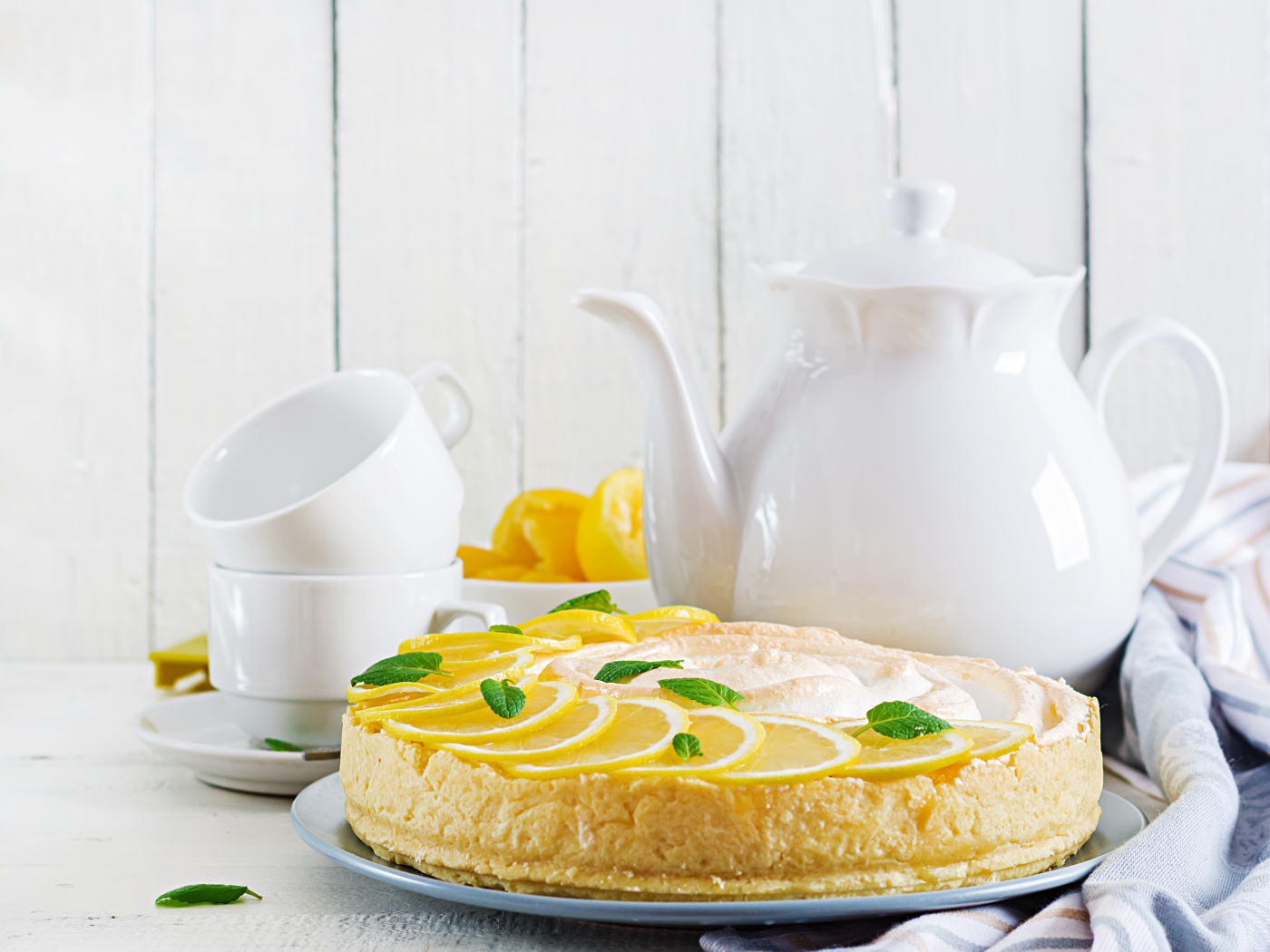 Вкусный песочный пирог с лимоном на столе с чашками и чайником