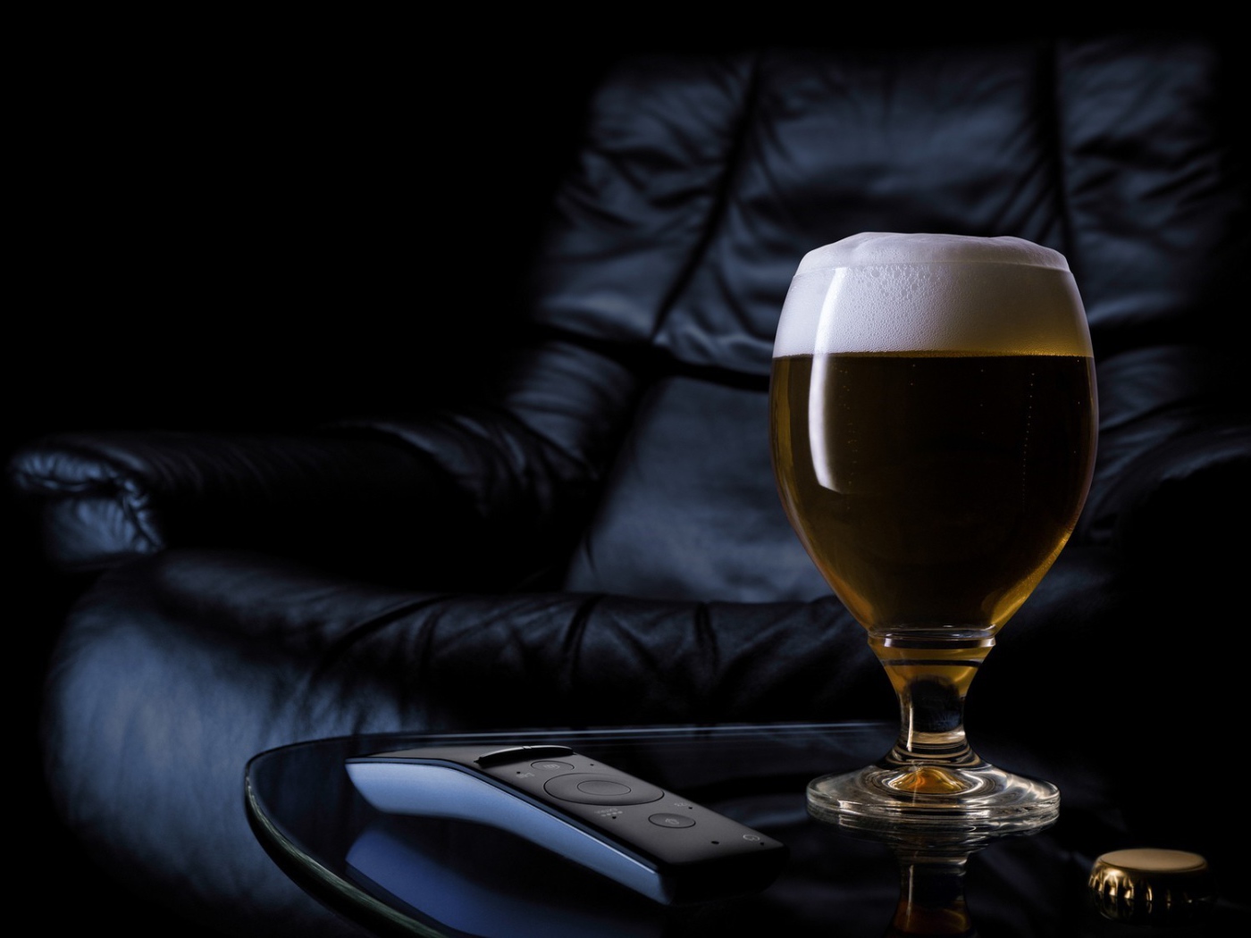 Бокал пива на фоне черного кожаного кресла