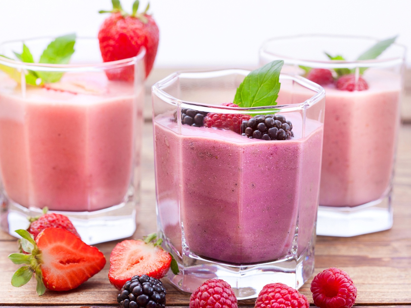 Ягодное смузи в стаканах на столе с ягодами малины, черники и клубники
