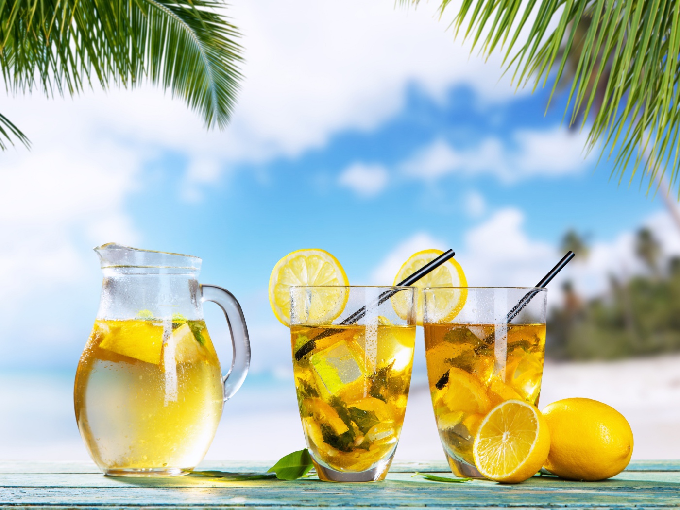 Графин и два стакана лимонада на столе на тропическом пляже
