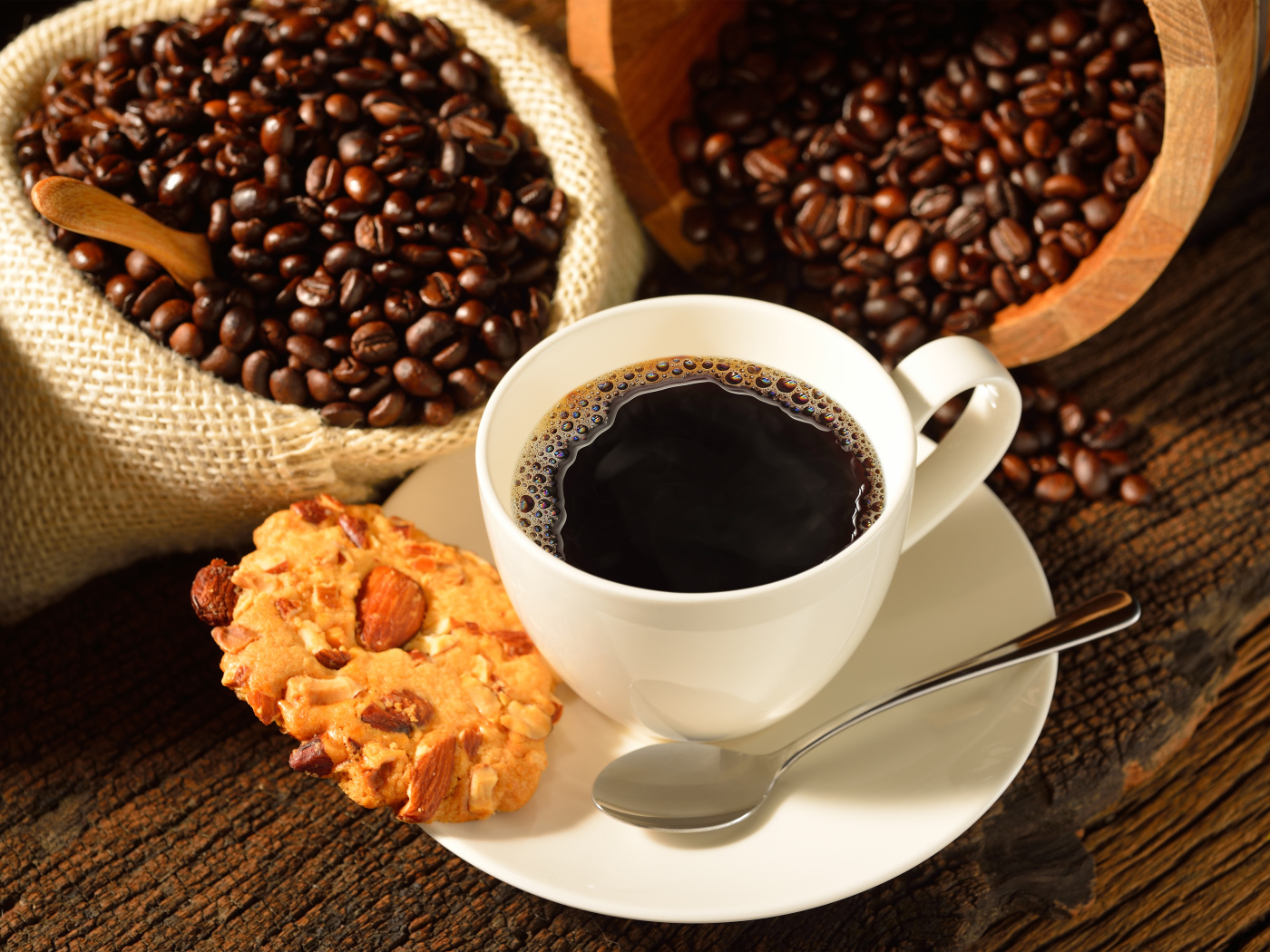 Кофейные зерна на столе с белой чашкой и печеньем